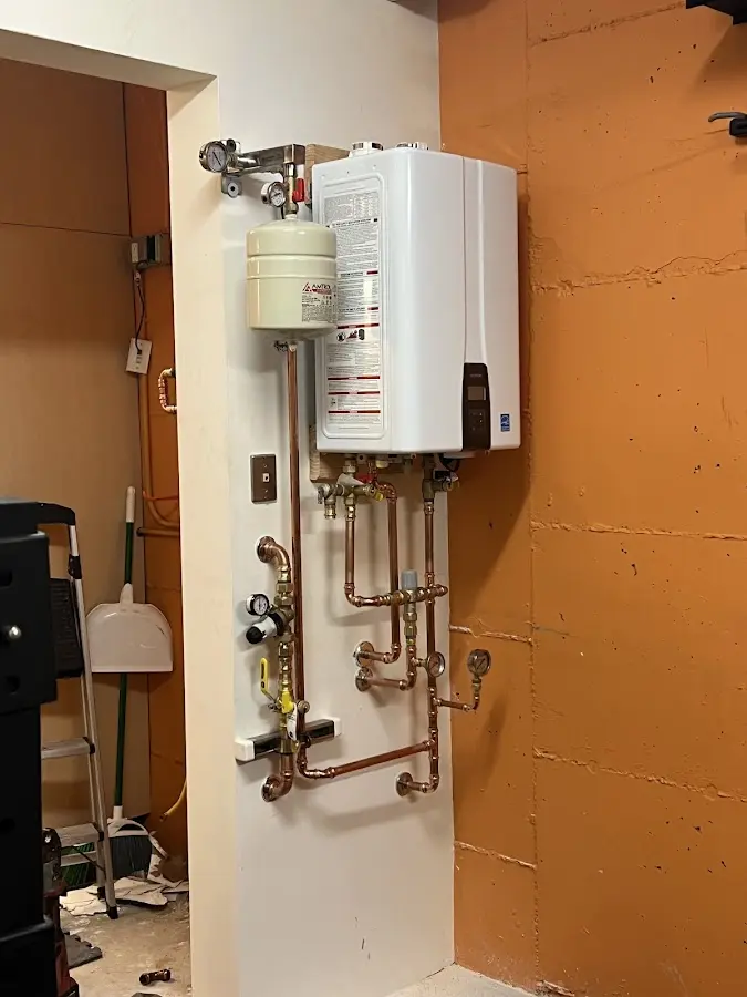 Plumbing technician inspecting water heater connections in Bergenfield